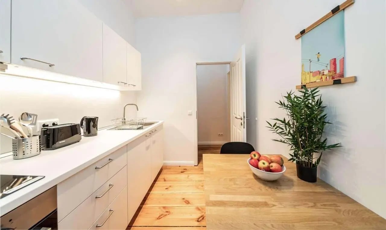 White cabinets sink toaster wooden table apples kitchen at Apartment in Berlin Student Accommodation