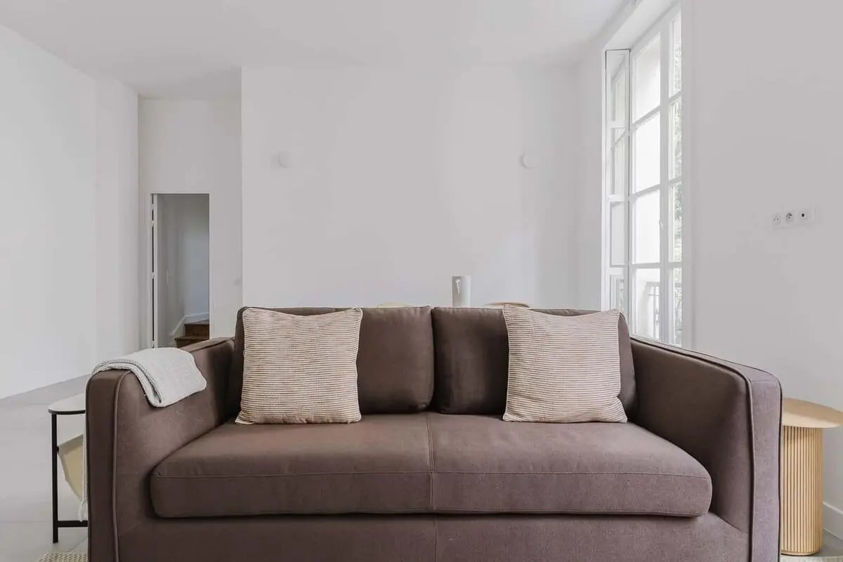 Brown sofa striped pillows light blanket living room at Rue Charlot in Paris Student Accommodation