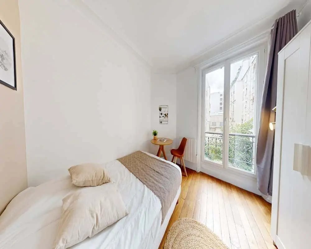 Bed with pillows blanket small table chair window bedroom at Room in 61 Rue des Cloys, 75018 Paris, France in Paris Student Accommodation
