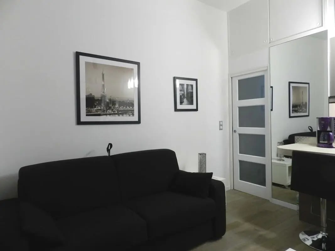 Black sofa framed artwork mirrored door living room at Studio in Rue Poissonnière, 75002 Paris, France in Paris Student Accommodation