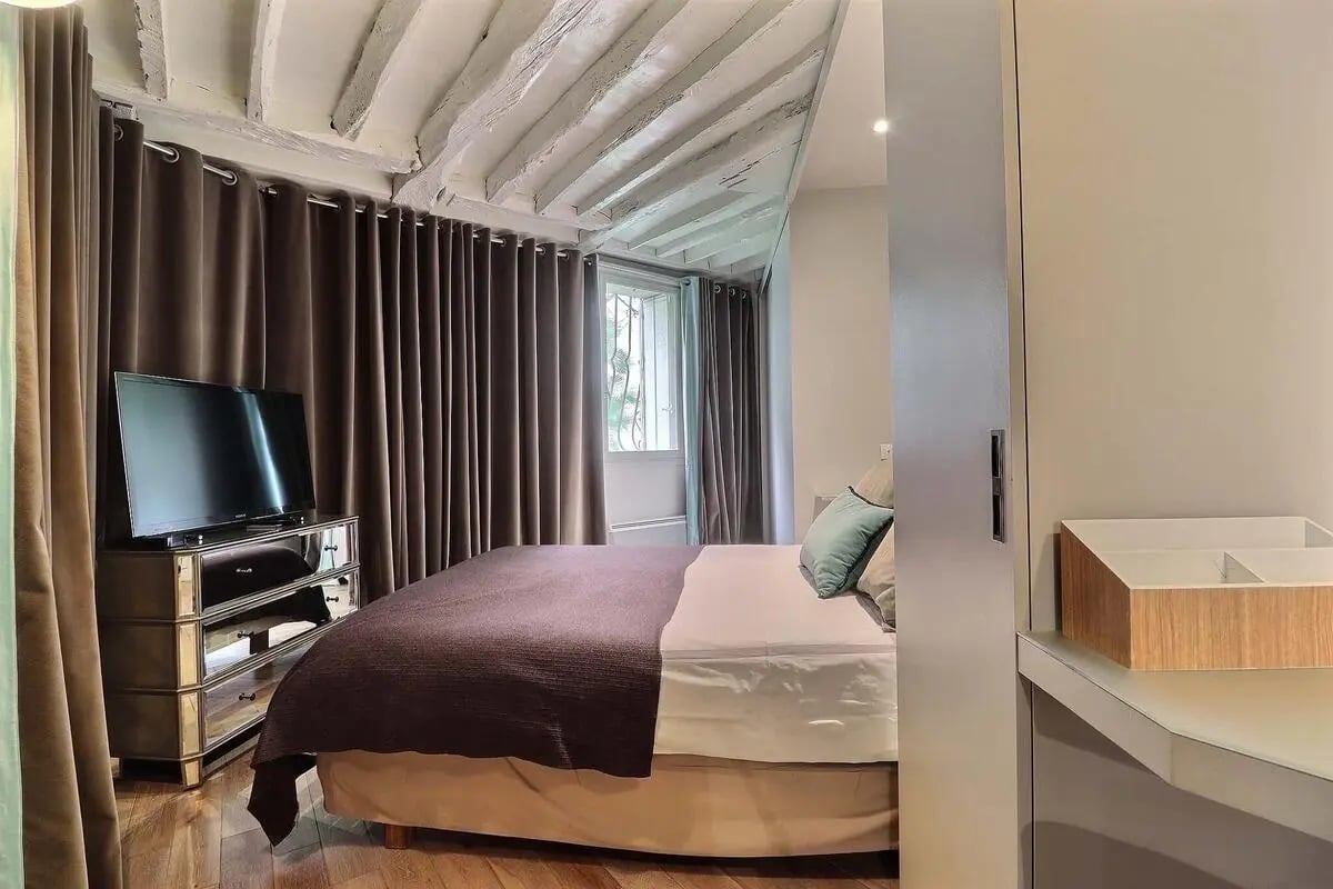 Bed television dresser mirror bedroom with beamed ceiling bedroom at Apartment 1 bedroom 53m² in Paris Student Accommodation