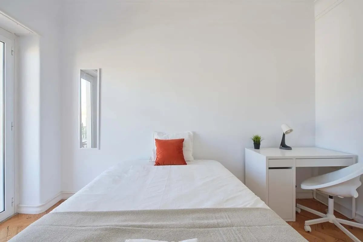 Bed with orange pillow, desk and chair bedroom at Bedroom in a 9-Bedroom Apartment in Rua Jorge Ferreira de Vasconcelos, Lisbon - Room 1 in Lisbon Student Accommodation