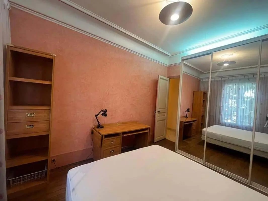 Bookshelf desk lamp and bed reflected in mirrored closet bedroom at RUE MEYNADIER in Paris Student Accommodation