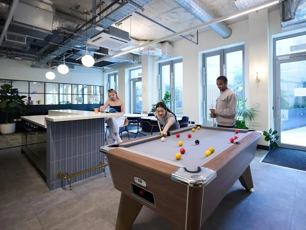 Pool table with players in lounge area at Great Court in London Student Accommodation