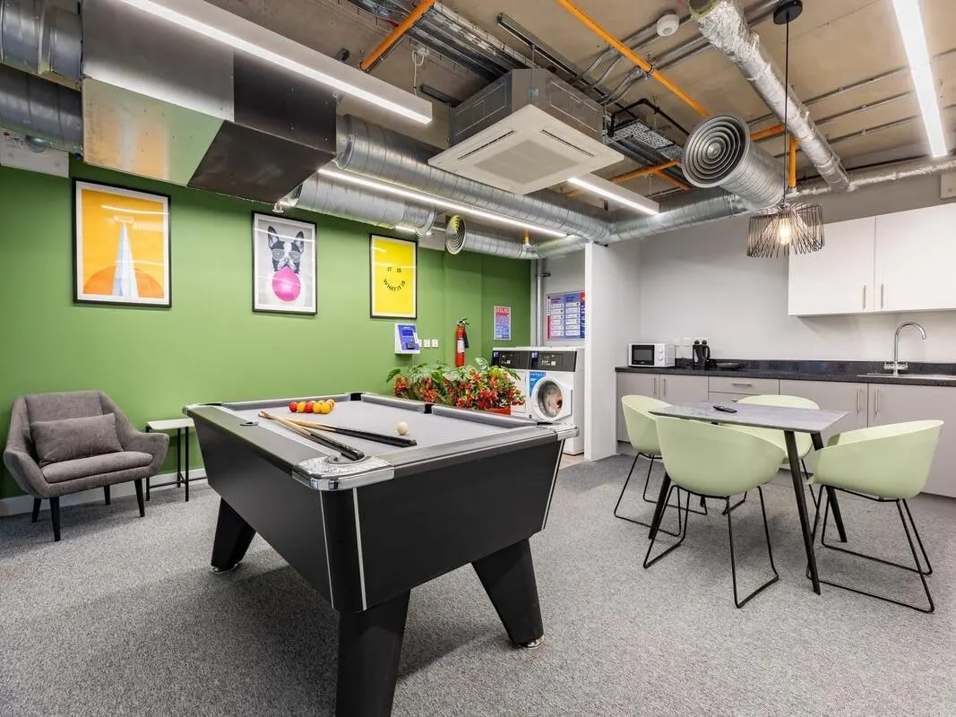 Pool table chairs laundry and kitchen lounge at Venue Studios in London Student Accommodation