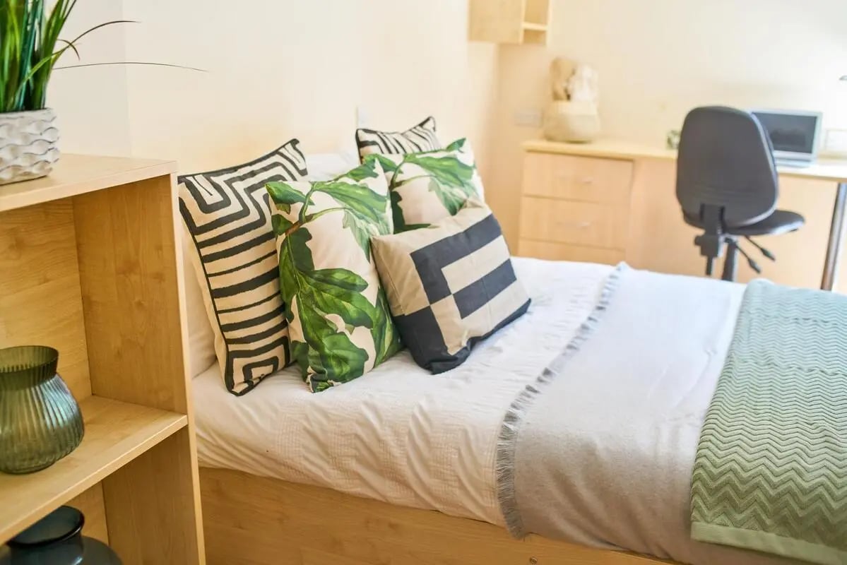 Bed with decorative pillows and desk with chair bedroom at Rockingham House in Sheffield Student Accommodation