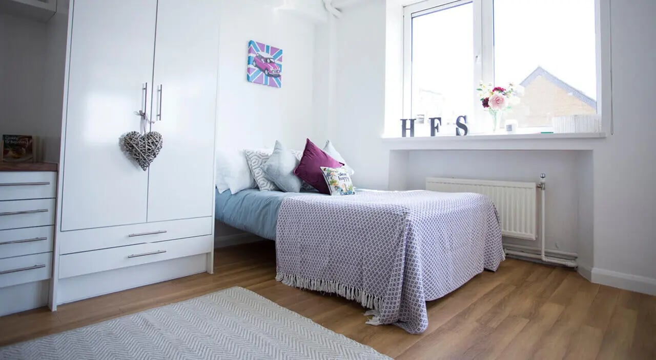 Bed with patterned blanket wardrobe and rug bedroom at Portobello Garrow House in London Student Accommodation