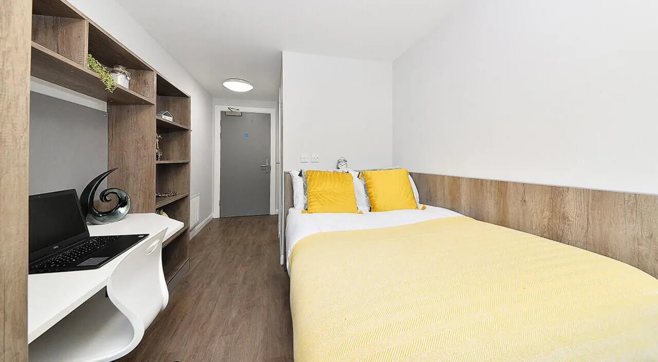 Bed laptop bookshelf and door bedroom at The Mill House in Edinburgh Student Accommodation