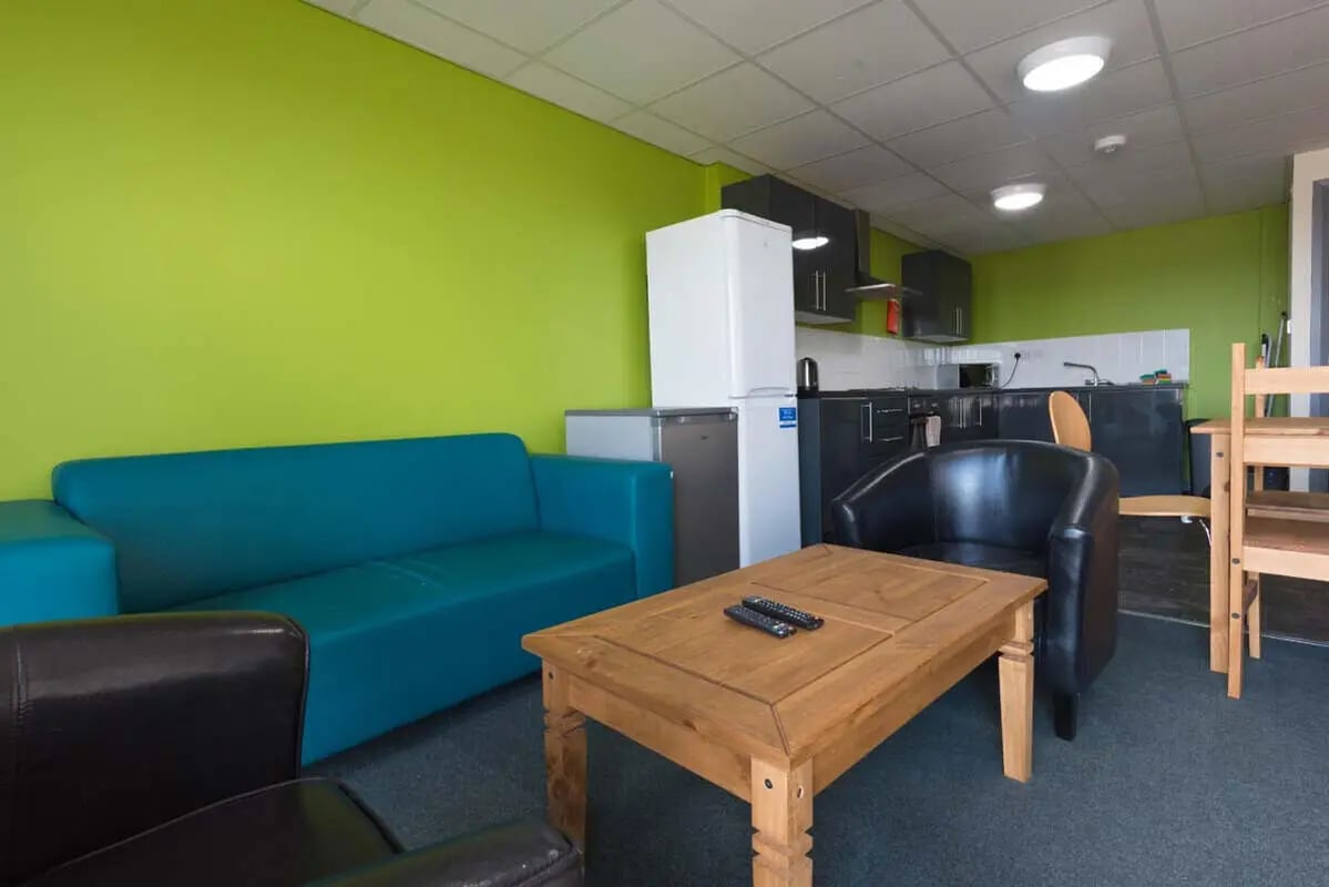 Blue sofa coffee table and kitchen area living room at Stoke Student Village in Stoke-On-Trent Student Accommodation