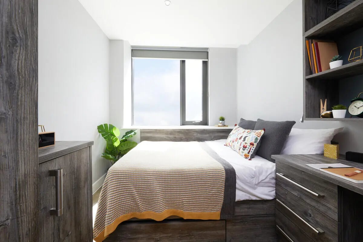 Bed with patterned pillows and blanket bedroom at Collegiate Crown Place Cardiff in Cardiff Student Accommodation