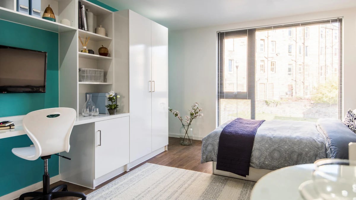 Desk chair TV white wardrobe and bed bedroom at Gateway Apartments in Edinburgh Student Accommodation