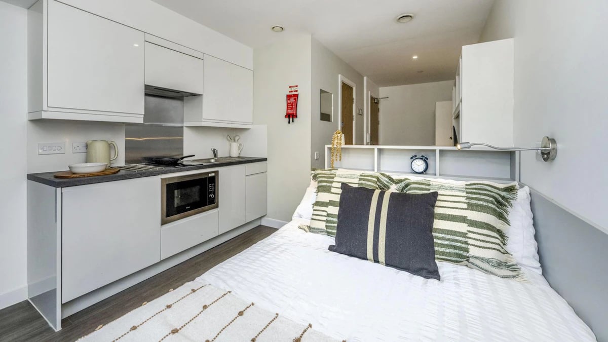Bed with kitchen unit and alarm clock studio at Holden Court in Brighton Student Accommodation