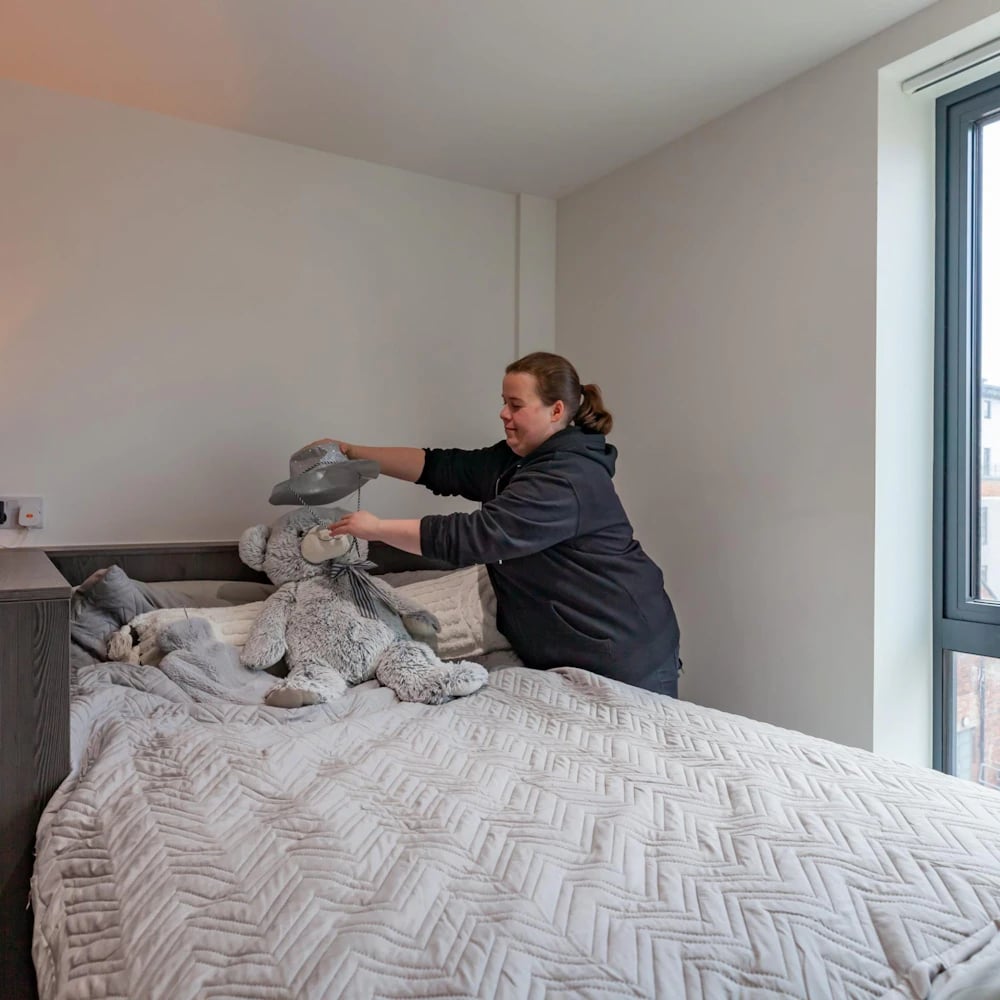 Girl placing hat on teddy bear bedroom at Opto Newcastle in Newcastle Upon Tyne Student Accommodation