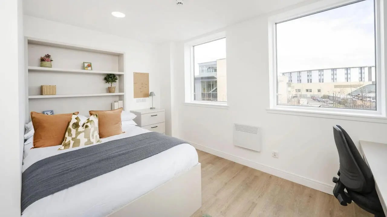 Bed with pillows shelves dresser desk and chair bedroom at Discovery Studios in Dundee Student Accommodation