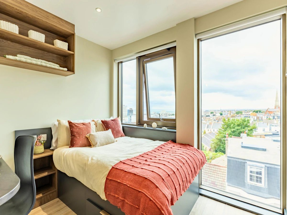 Bed pillows blanket shelves desk chair window bedroom at Crown House Brighton in Brighton Student Accommodation