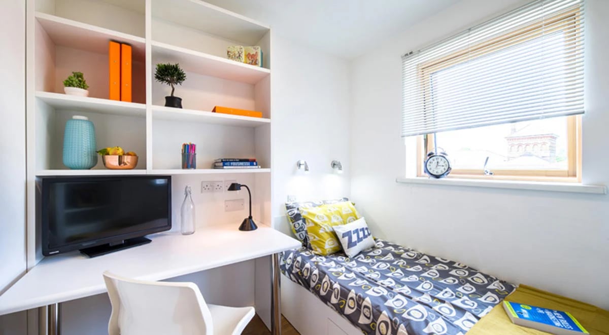 Desk bed shelving with television alarm clock bedroom at Academic House in London Student Accommodation