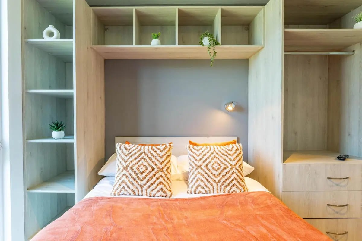 Bed with patterned pillows and orange throw Bedroom at Abeleven in Aberdeen Student Accommodation