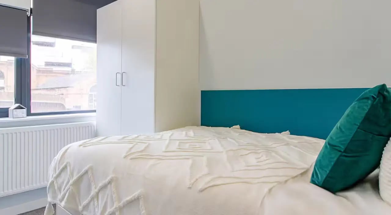 Bed with white textured blanket and teal headboard bedroom at Urban Student Village in Coventry Student Accommodation