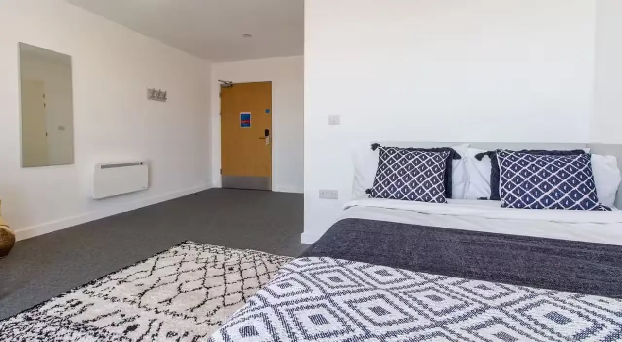 Bed with patterned pillows rug and door Bedroom at The Croft in Derby Student Accommodation
