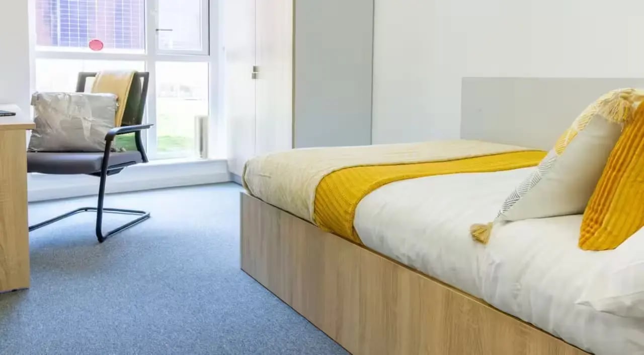 Bed with yellow throws and pillows bedroom at The Croft in Derby Student Accommodation