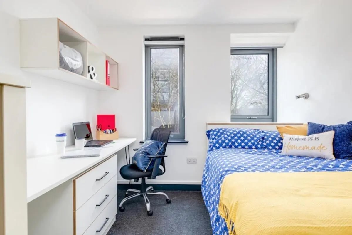 Desk with laptop bed with blue stars pillow Bedroom at Fulham Palace Studios in London Student Accommodation