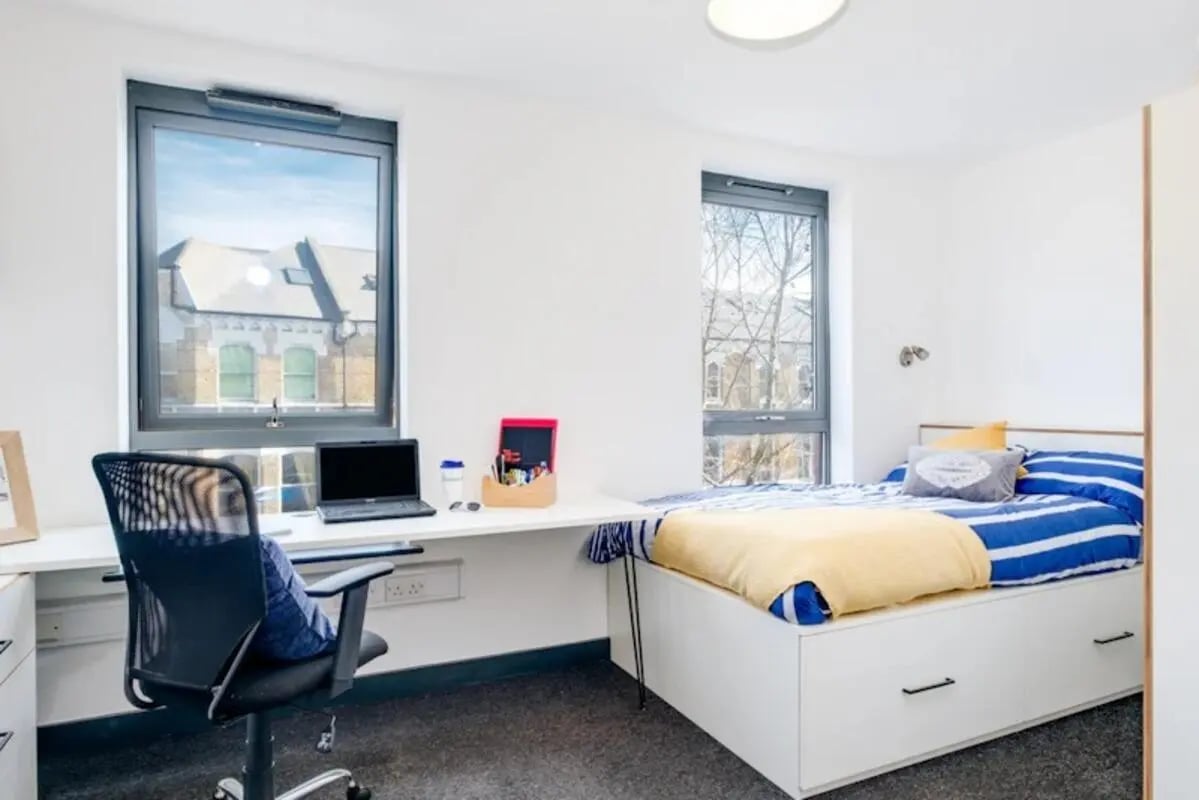 Bed desk chair laptop pens two windows bedroom at Fulham Palace Studios in London Student Accommodation