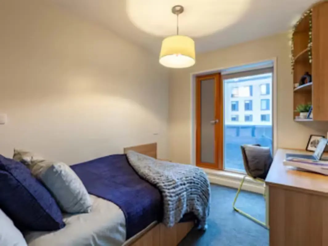 Bed with blue pillows desk and window bedroom at Kendrick Hall in Reading Student Accommodation