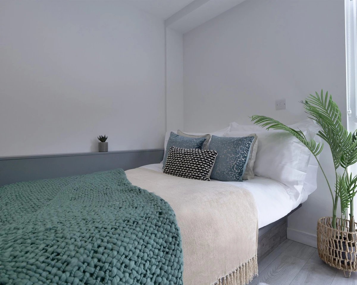 Bed with pillows throws and potted plant bedroom at Urban Hub in Preston Student Accommodation