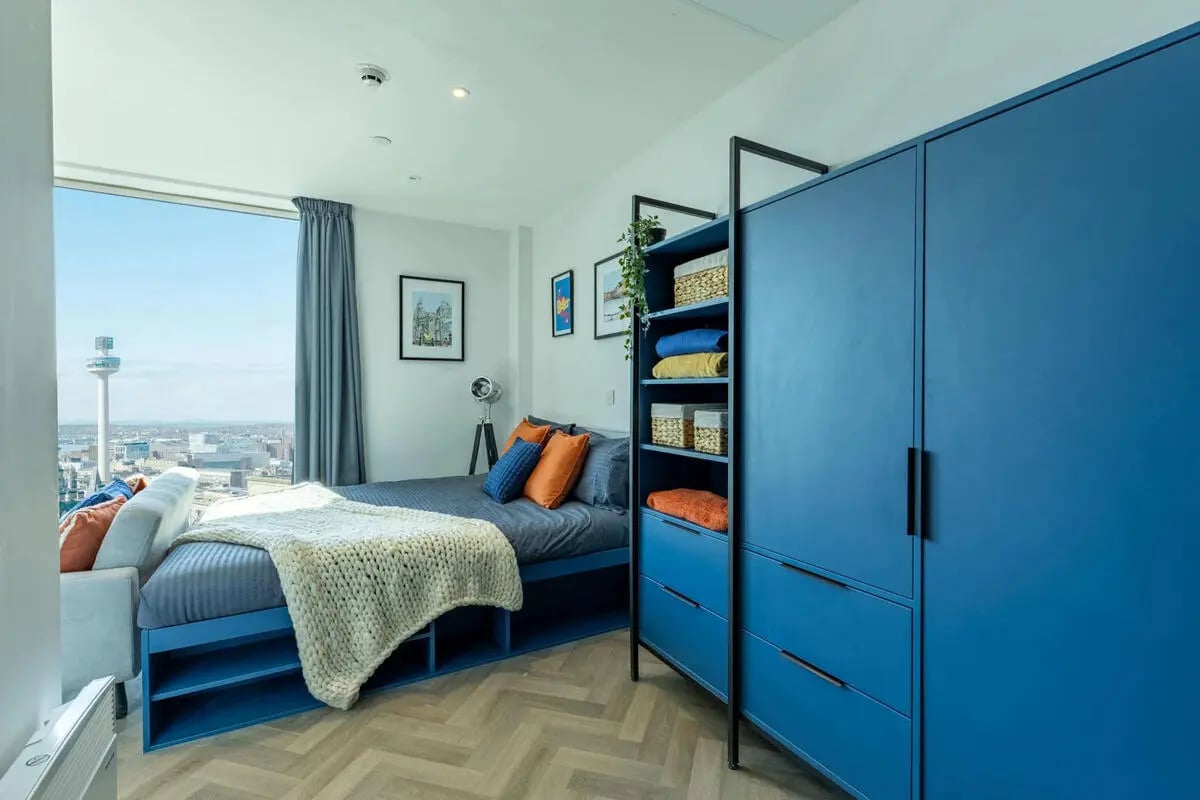 Blue wardrobe bed with knit blanket bedroom at Limelight in Liverpool Student Accommodation
