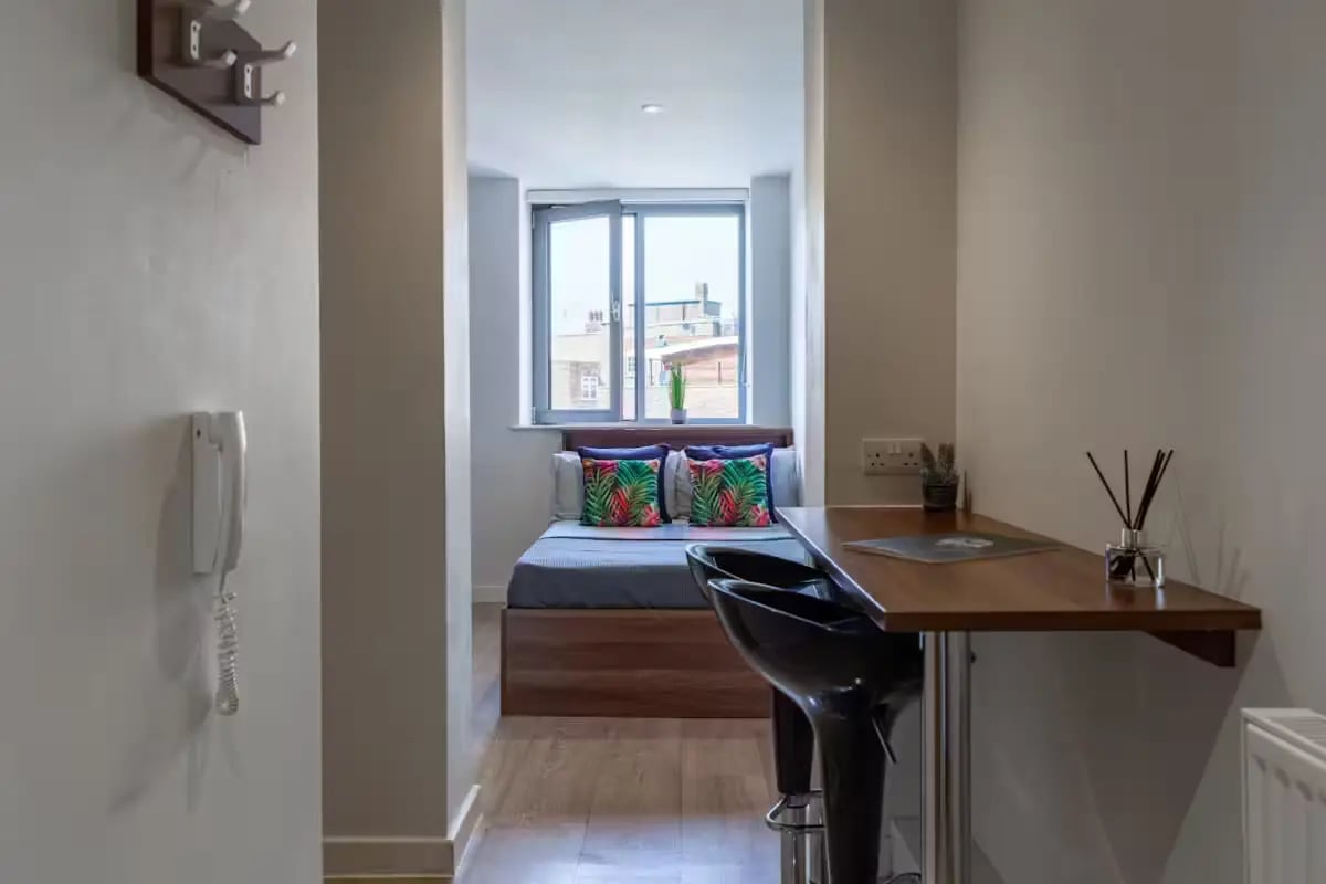 Bed with patterned pillows bar stools study area bedroom at Central Studios - London in London Student Accommodation