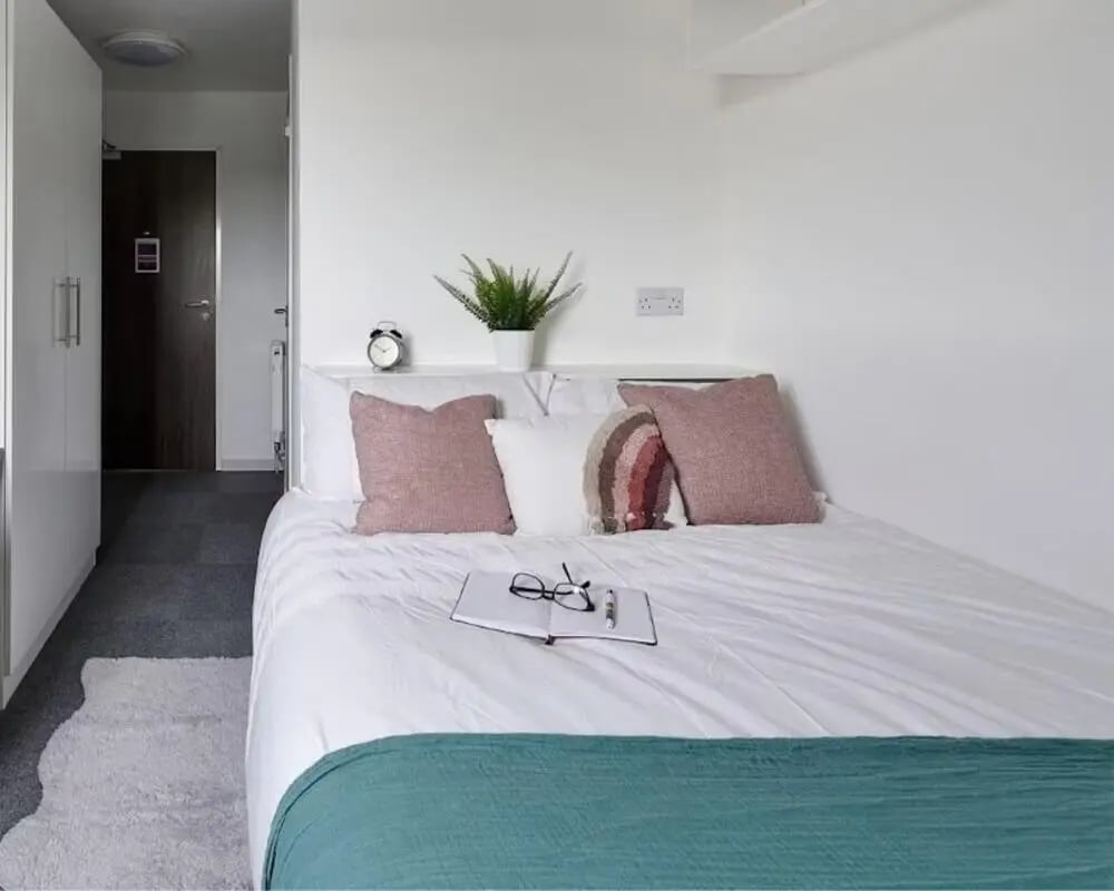 Bed pillows alarm clock plant rug Bedroom at Frobisher House in Plymouth Student Accommodation