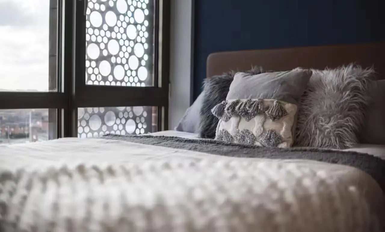 Bed with grey pillows and patterned window Bedroom at The Vantage in Nottingham Student Accommodation