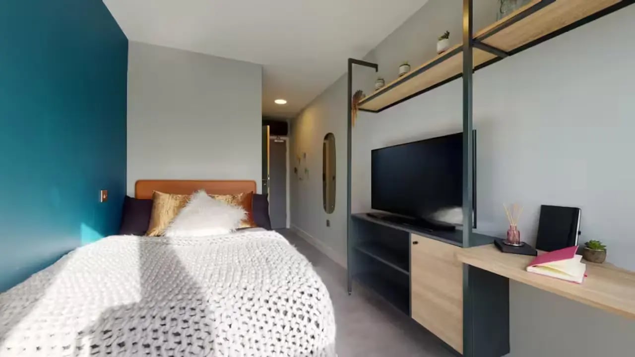 Bed with plush covers TV and desk bedroom at Guilden Village in Guildford Student Accommodation