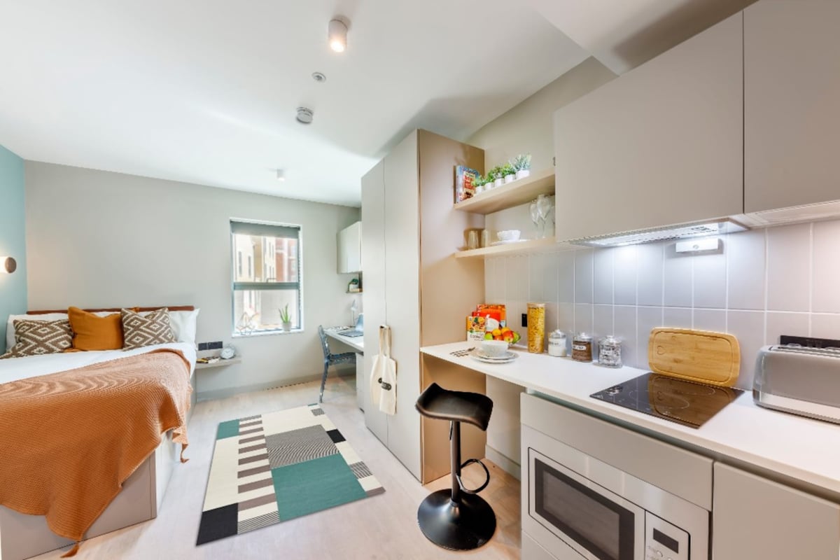 Bed study desk kitchen counter and stools studio apartment at The Garage Egham in Egham Student Accommodation