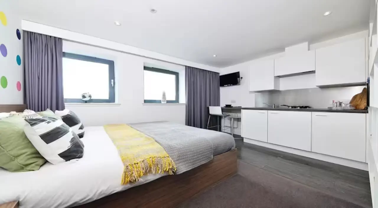 Bed kitchen area with white cabinets and TV studio apartment at Gallery Apartments in Glasgow Student Accommodation