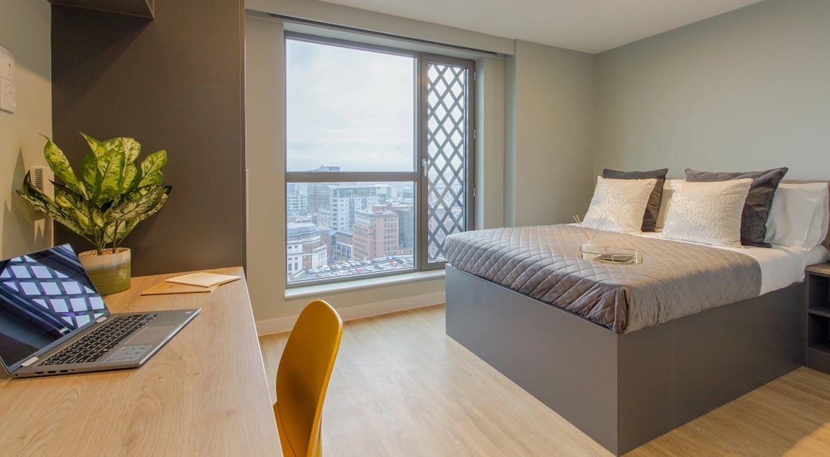 Laptop desk plant bed pillows city view bedroom at Symons House in Leeds Student Accommodation