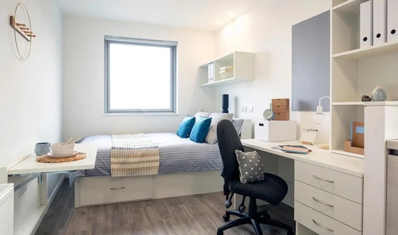 Bed desk and shelving unit student room at Westcombe House in London Student Accommodation
