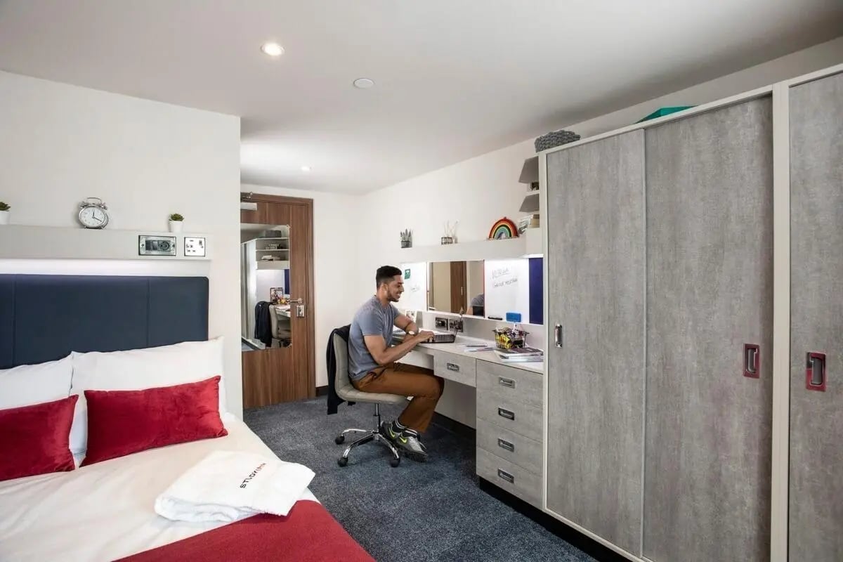 Man at desk bed wardrobes bedroom study area at Reynard House in Leicester Student Accommodation
