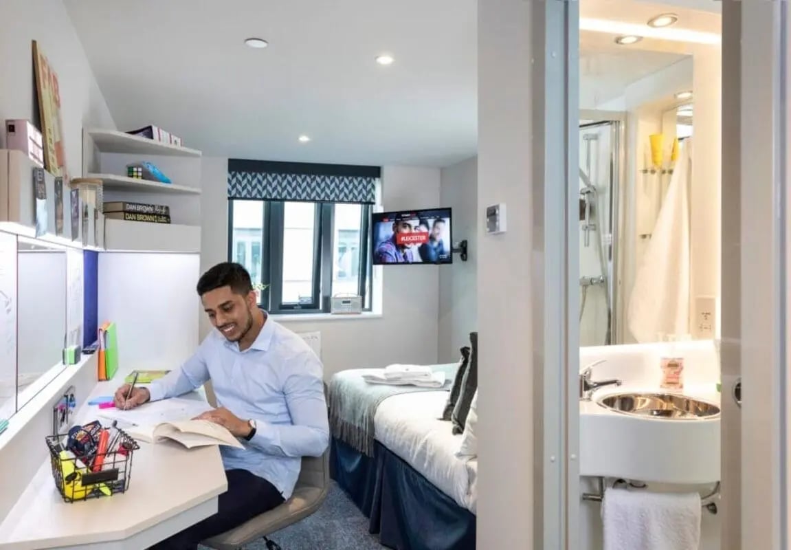 Student studies at desk by bed and bathroom at Reynard House in Leicester Student Accommodation