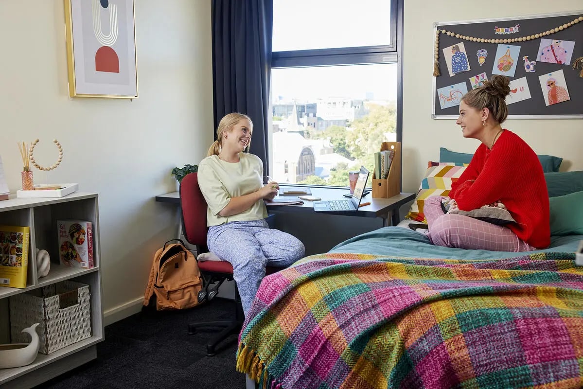 Two students study and relax in a dorm room bedroom at Broadway x Scape in Sydney Student Accommodation