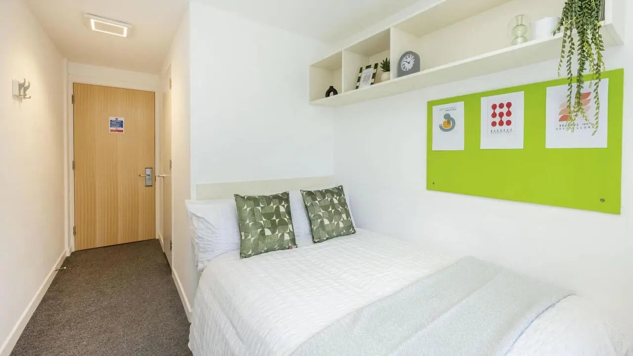 Bed with green pillows and framed art Bedroom at Hollingbury House in Brighton Student Accommodation