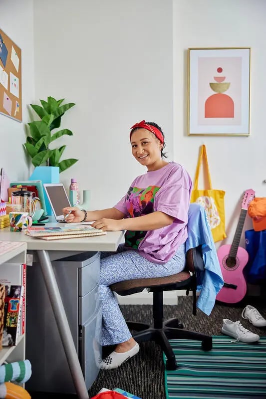 Woman at desk with laptop and guitar study area at Mountain x Scape in Sydney Student Accommodation