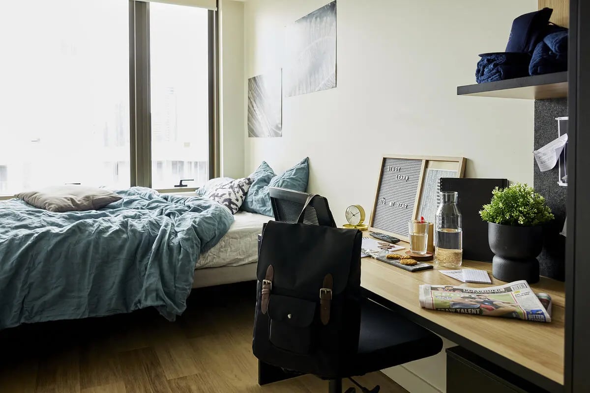 Bed pillows desk backpack and plant bedroom study area at Scape La Trobe in Melbourne Student Accommodation