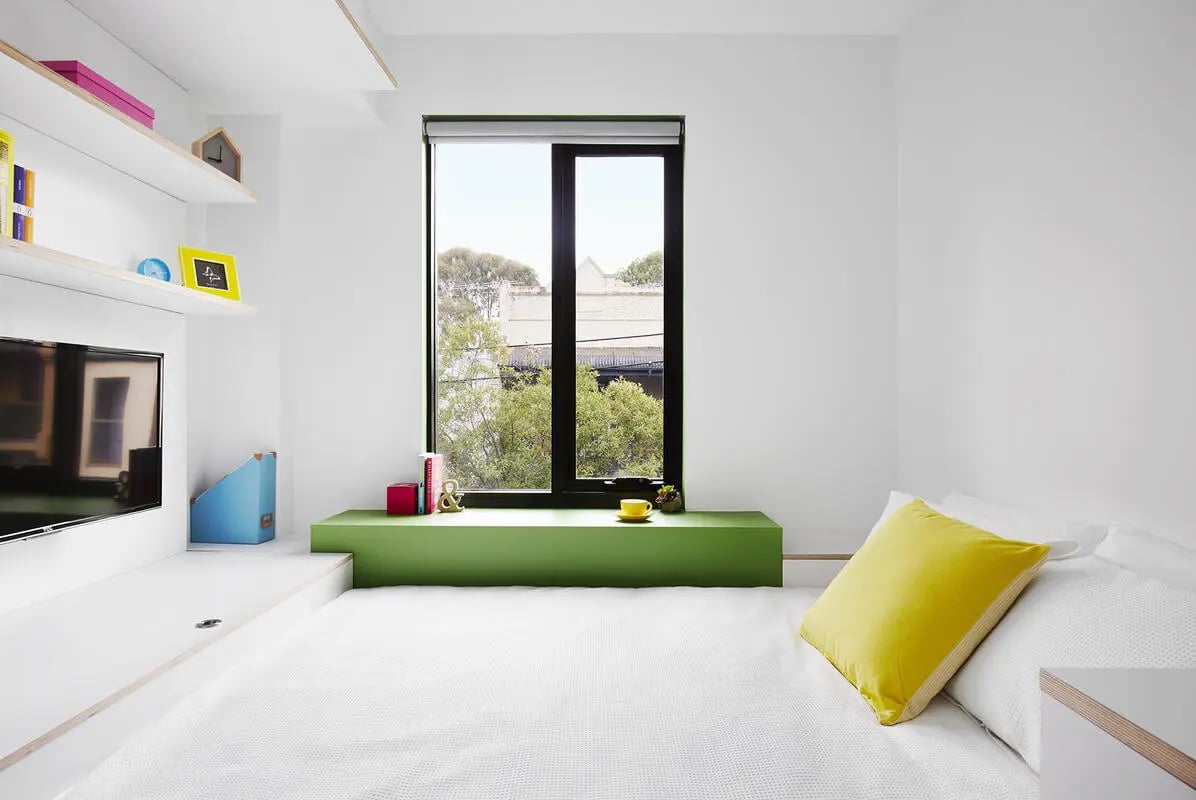 Bed with yellow pillow window and shelves bedroom at Scape Abercrombie in Sydney Student Accommodation