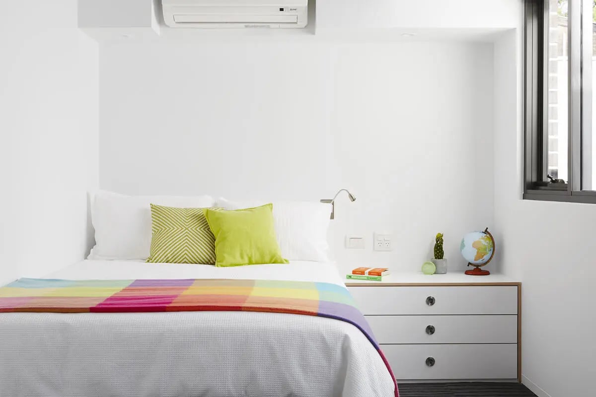 Bed with colorful throw white pillows bedside cabinet Bedroom at Scape Abercrombie in Sydney Student Accommodation