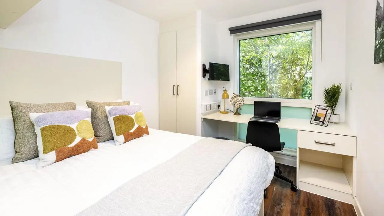 Bed desk lamp laptop and pillows bedroom at Hollingbury House in Brighton Student Accommodation