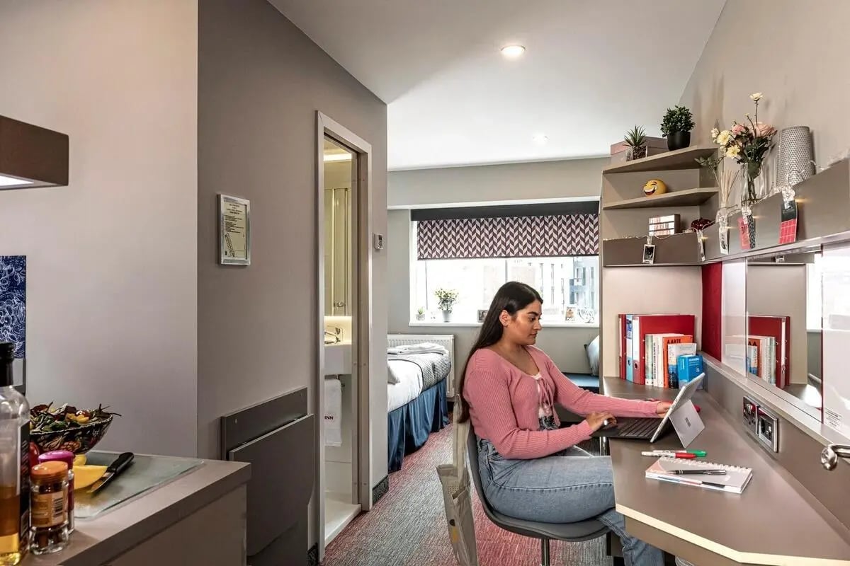 Student working at desk near bed and bathroom study bedroom at Study Inn Talbot Street Nottingham in Nottingham Student Accommodation