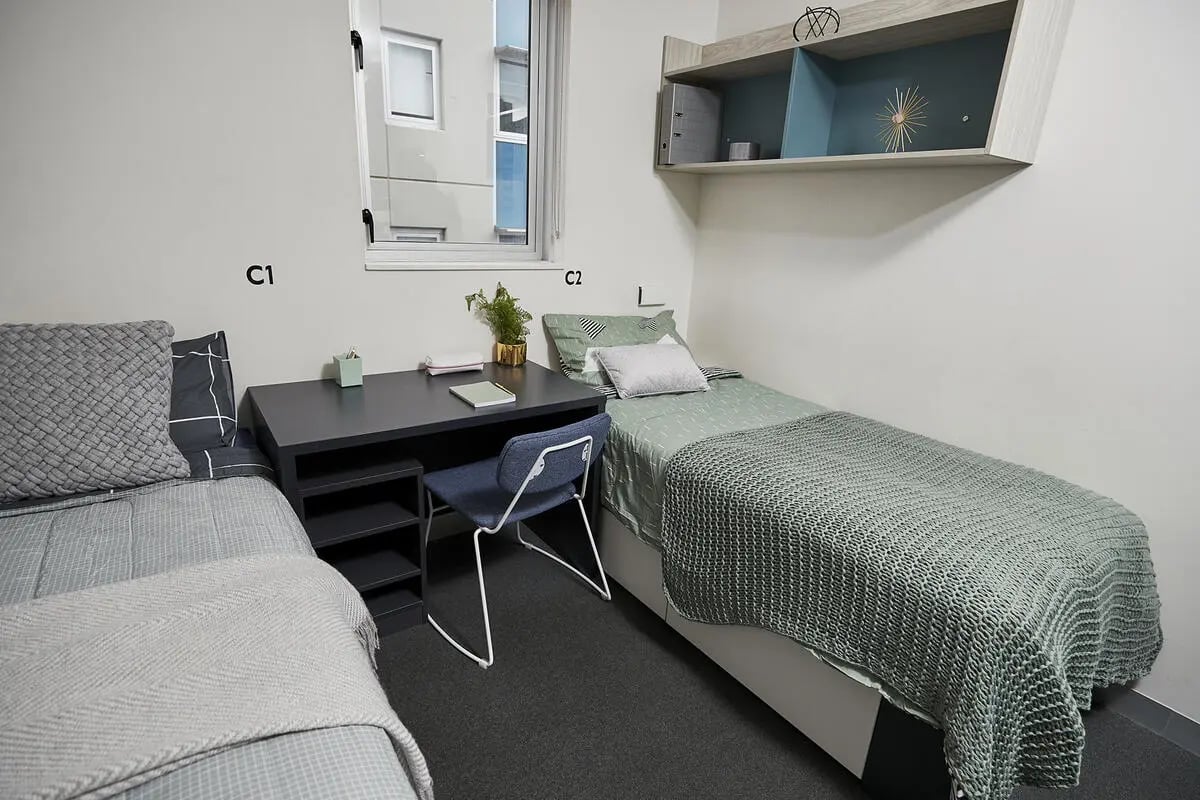 Two beds desk chair shelf bedroom at Scape Adelaide Central in Adelaide Student Accommodation
