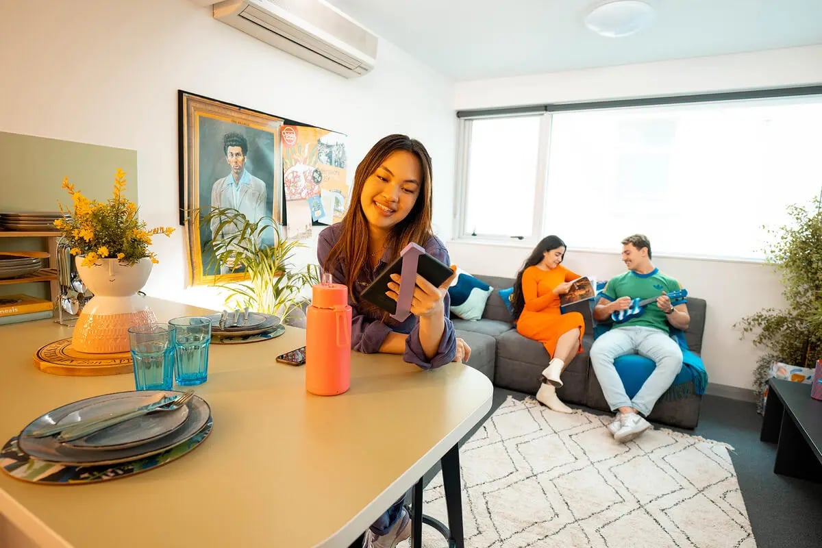 Table setting with students relaxing living room at Scape Adelaide Central in Adelaide Student Accommodation
