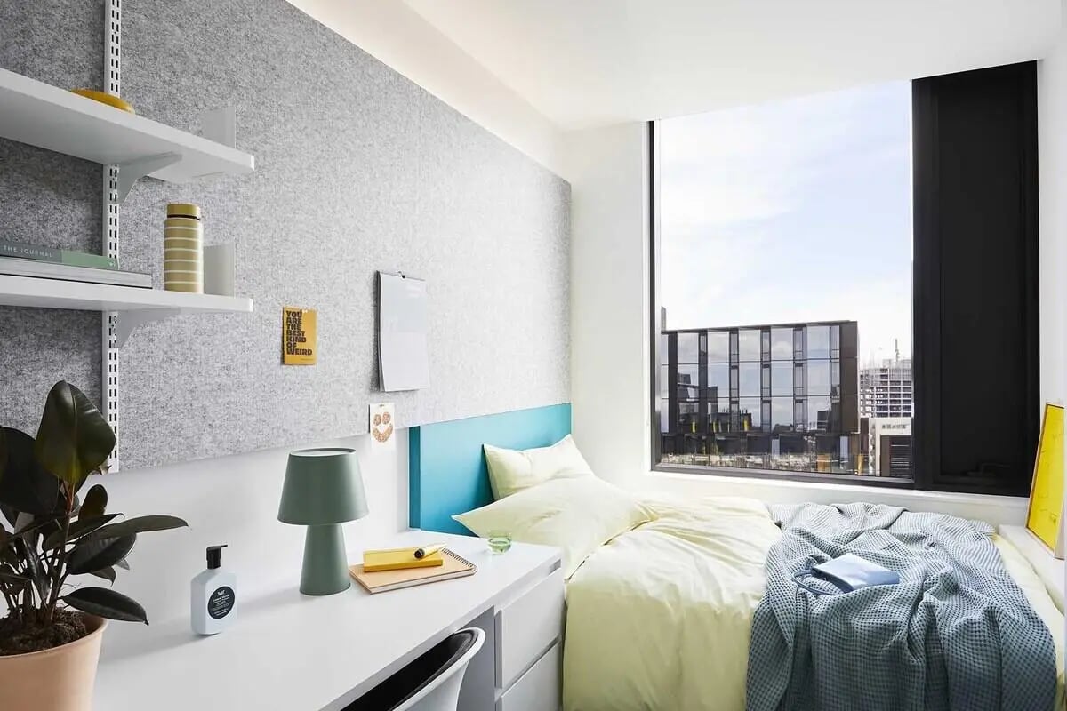 Bed desk plant and window view student bedroom at Scape Lincoln College in Melbourne Student Accommodation